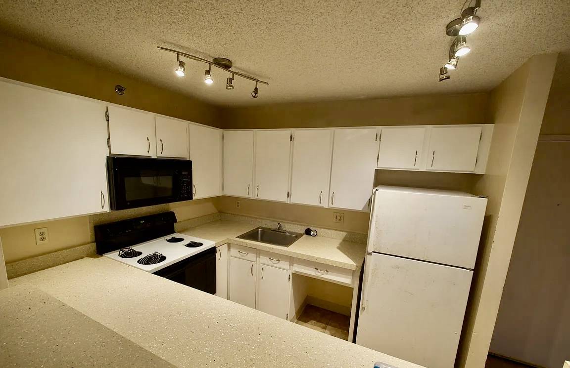 A kitchen with white cabinets and a black microwave.